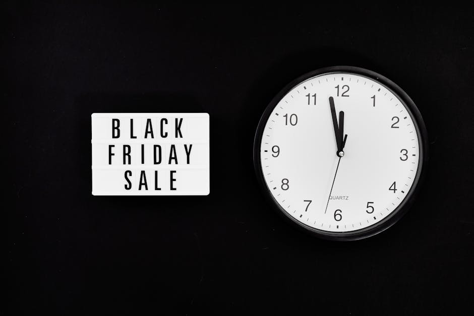 A black background featuring a rectangular lightbox sign with black text reading 'BLACK FRIDAY SALE' positioned to the left, and a round white wall clock with black numerals and hands showing approxim