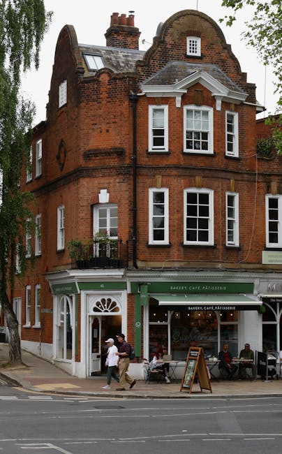 The image features a floral bouquet arranged in a clear glass vase, placed on a table outside a bakery café in a historic red brick building. The bouquet includes a mix of fresh flowers with soft pin